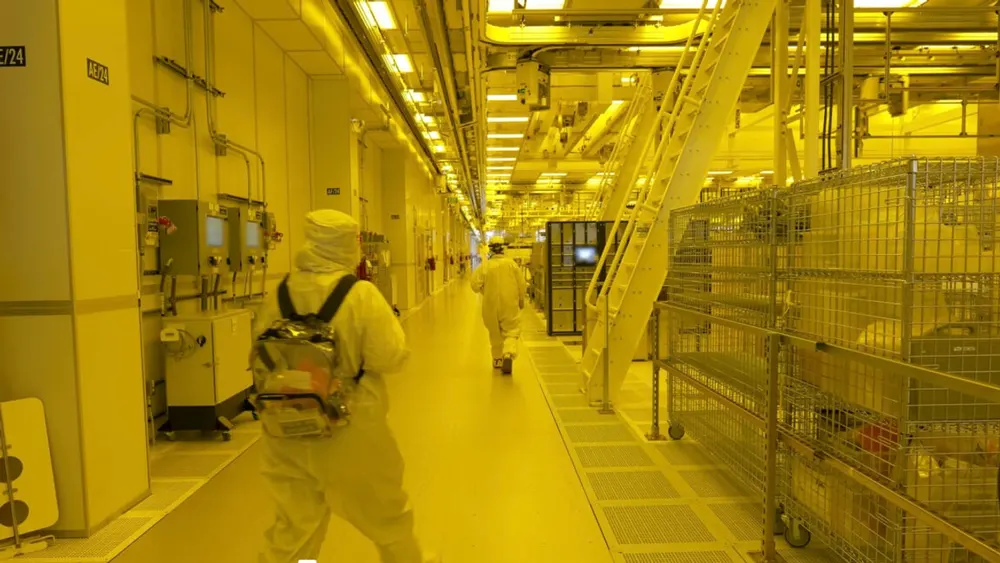Interior of modern Intel semiconductor fabrication facility showing overhead automated wafer transport tracks and cleanroom equipment