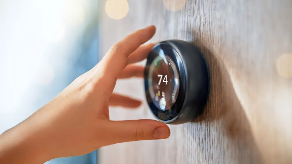Circular digital wall display of a legacy Nest Learning Thermostat installed in a residential hallway