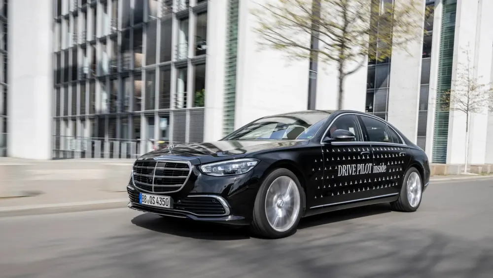 Mercedes-Benz EQS test vehicle displaying illuminated turquoise cyan exterior indicator lamps for automated driving mode