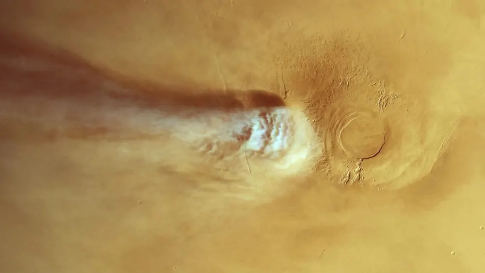 Orbital satellite imagery of Mars showing the 1,000-mile white Arsia Mons Elongated Cloud trailing past volcanic calderas