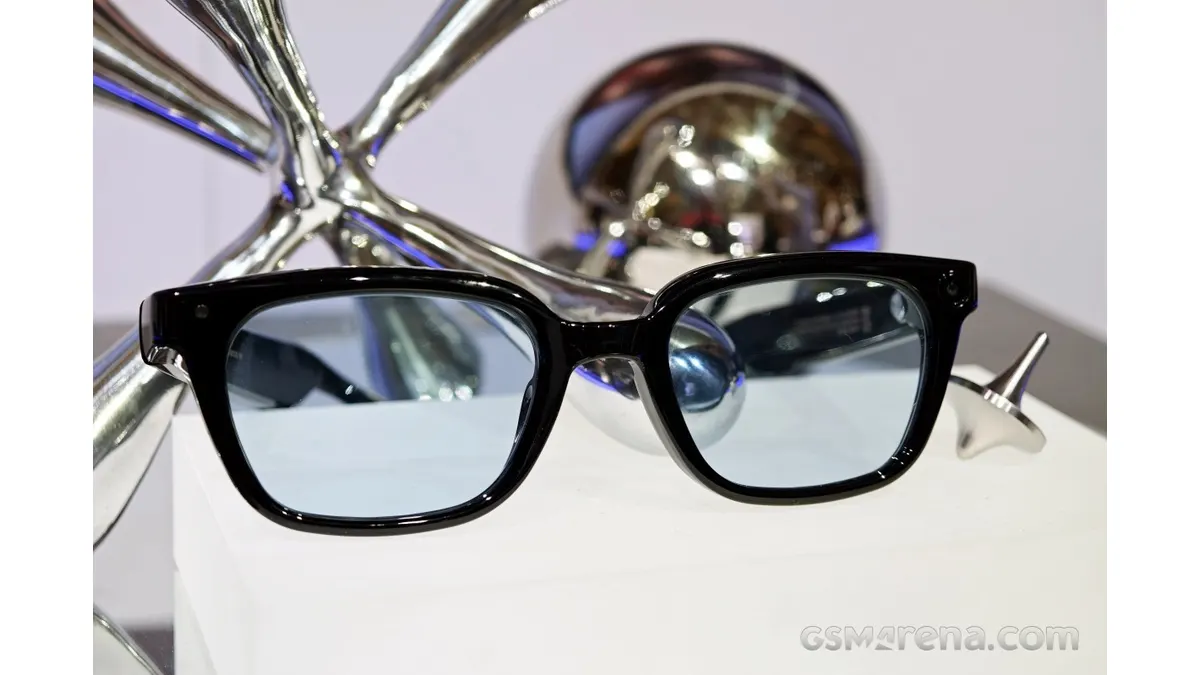 Black-framed Samsung smart glasses photographed against a metallic display backdrop.