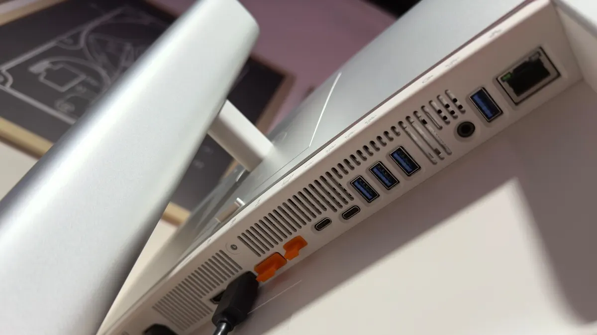 Close-up photograph of the silver Dell UltraSharp monitor's rear connection panel, showing USB ports, Ethernet, ventilation slots, and part of the stand.