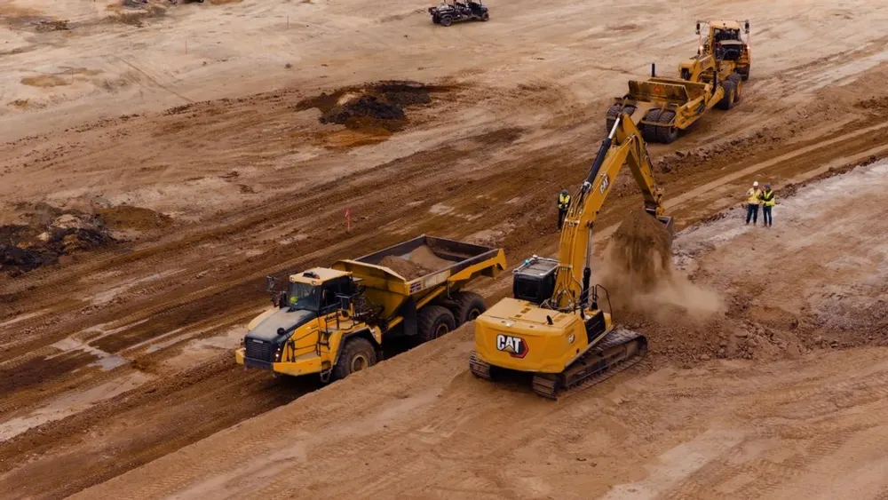 Autonomous 30-ton hydraulic excavator fitted with Bedrock Robotics perception and compute roof hardware digging on an earthmoving site