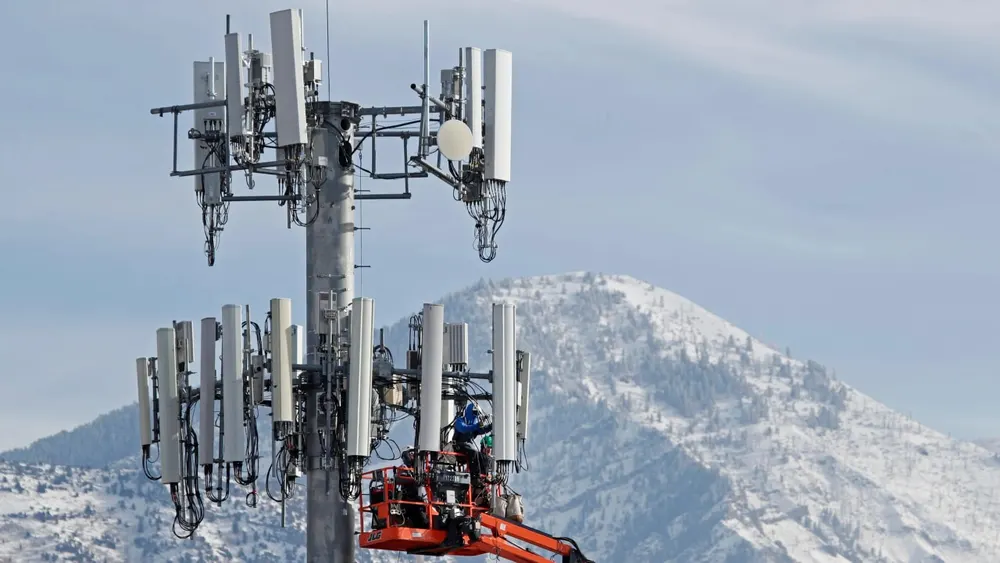 Cellular telecommunications tower against dusk sky with Starlink direct-to-cell satellite constellation overlay