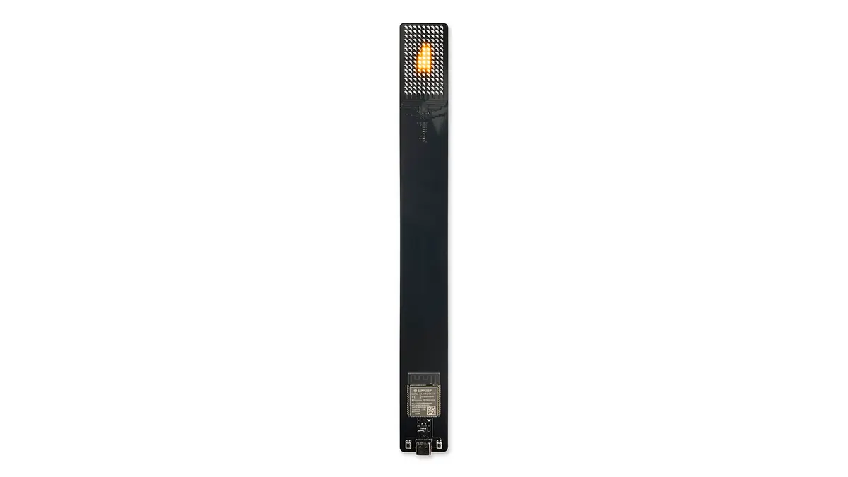 Front view of the black Arduboy Digital Candle, showing its narrow exposed circuit board and amber LED matrix displaying a simulated flame.