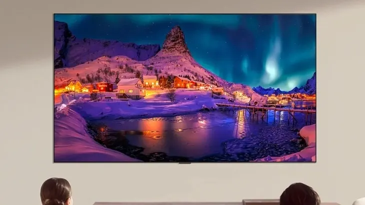 LG OLED65G6WUA mounted on a wall, displaying a northern-lights landscape, with viewers seated below; official LG marketing image